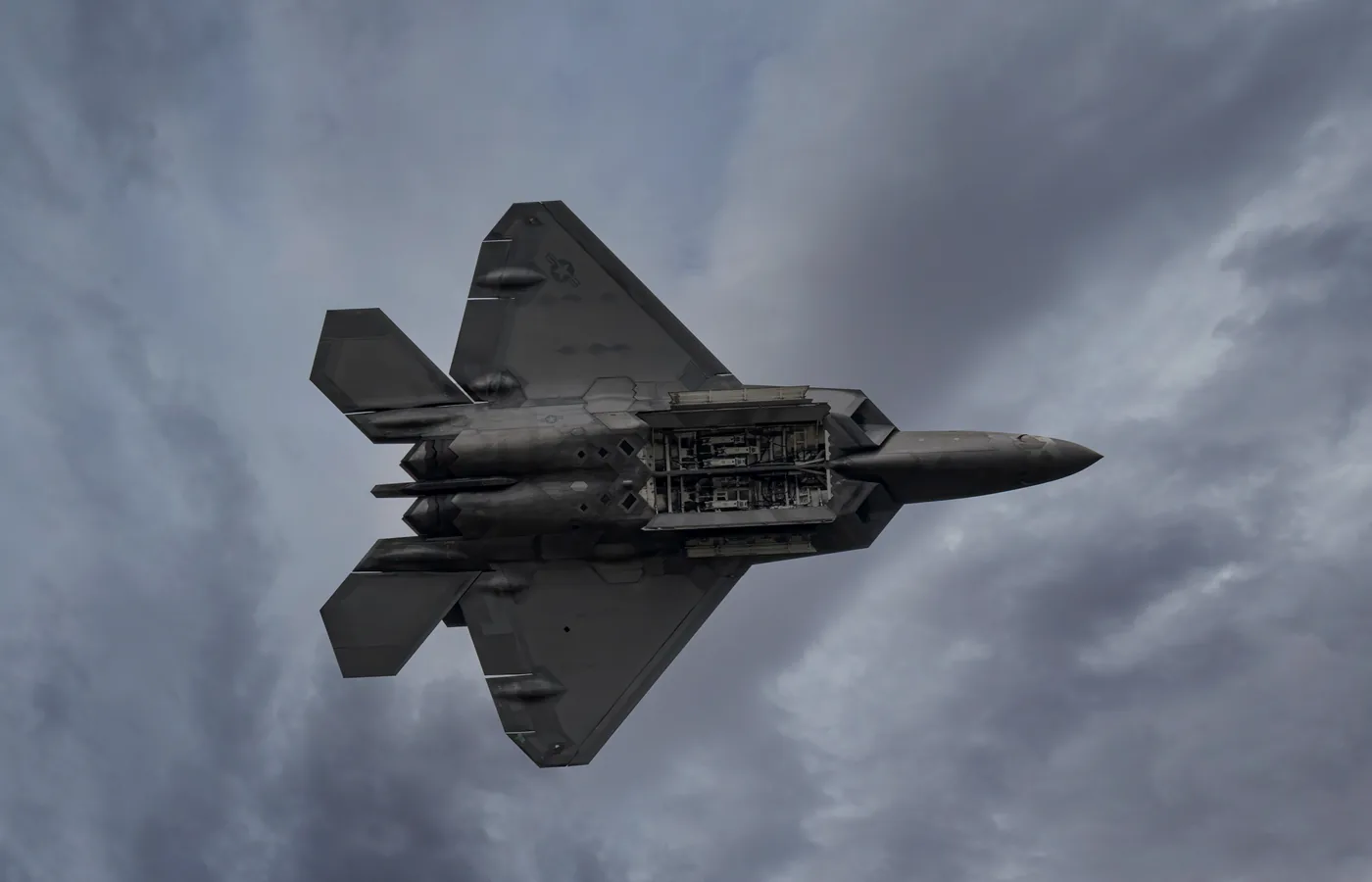 A jet aircraft with an exposed equipment bay in flight